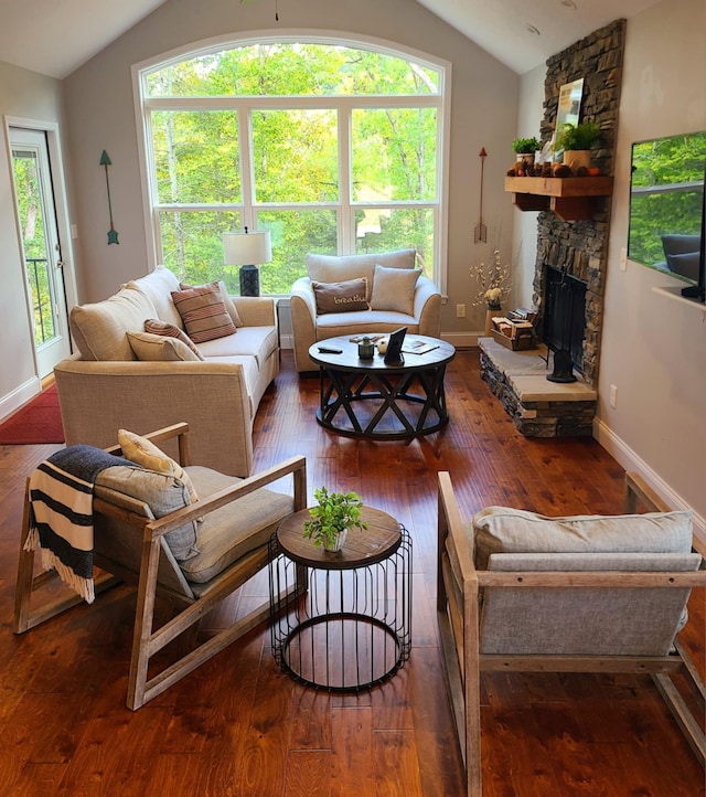 living room featuring lofted ceiling, dark wood-type flooring, and a stone fireplace