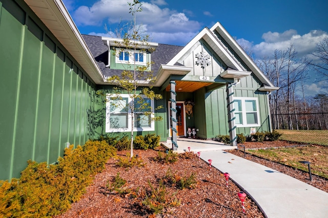 view of front facade featuring board and batten siding, fence, and a shingled roof