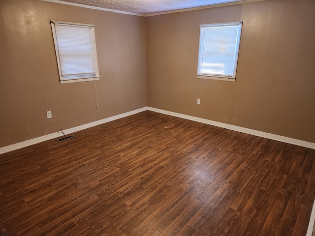 empty room featuring dark wood-type flooring and ornamental molding