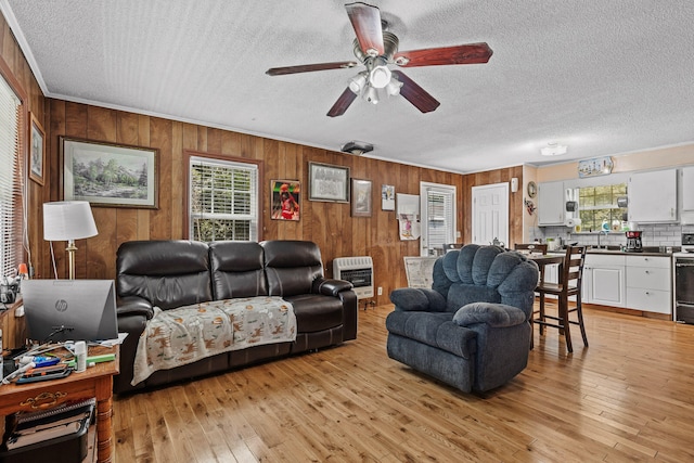 living room with a textured ceiling, heating unit, ceiling fan, and light hardwood / wood-style floors