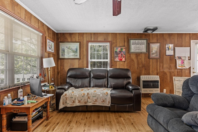 living room featuring ornamental molding, light hardwood / wood-style flooring, heating unit, and wood walls