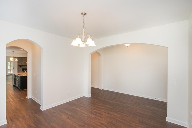 spare room featuring a chandelier and dark hardwood / wood-style flooring