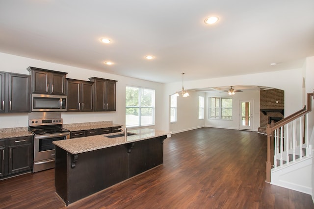 kitchen featuring a brick fireplace, dark hardwood / wood-style floors, a breakfast bar area, and stainless steel appliances