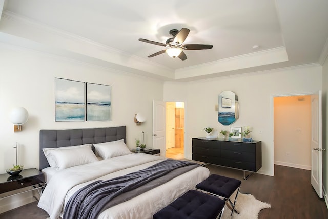 bedroom with ceiling fan, a raised ceiling, connected bathroom, ornamental molding, and dark hardwood / wood-style floors