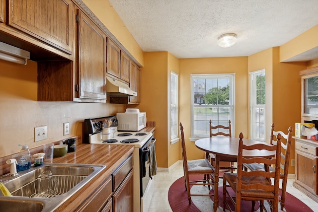 kitchen with a textured ceiling, white appliances, light tile patterned flooring, and sink