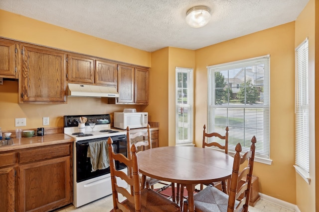 kitchen featuring light tile patterned floors, a textured ceiling, and white appliances