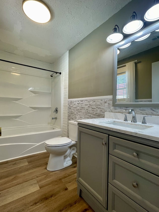 full bathroom featuring hardwood / wood-style floors, shower / bathing tub combination, decorative backsplash, vanity, and toilet