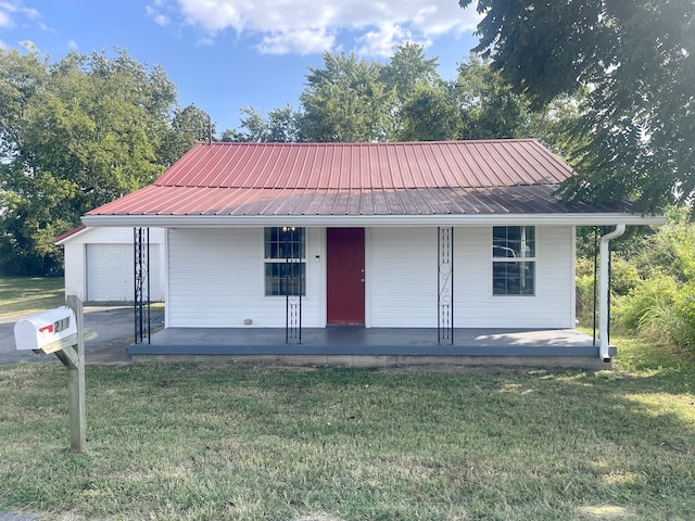 view of front of property with a garage, an outbuilding, a porch, and a front yard