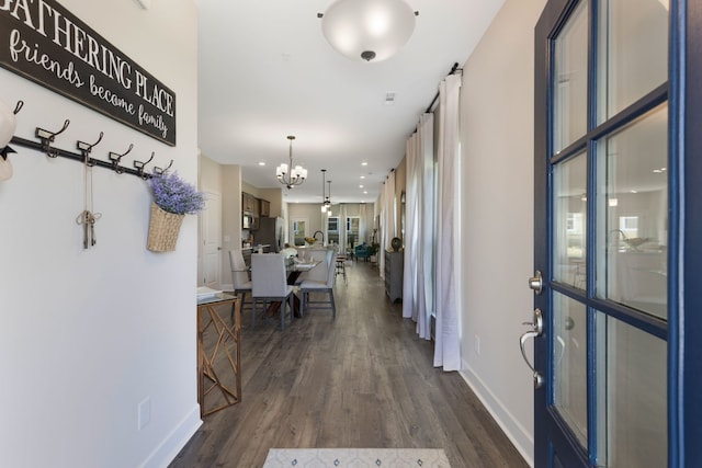 corridor featuring dark wood-type flooring and a chandelier