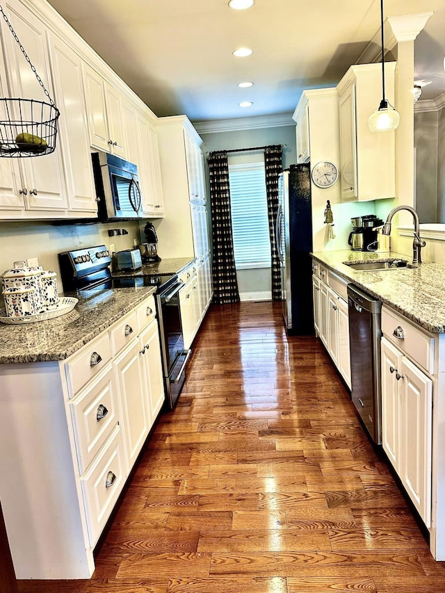 kitchen with appliances with stainless steel finishes, ornamental molding, hardwood / wood-style flooring, and sink