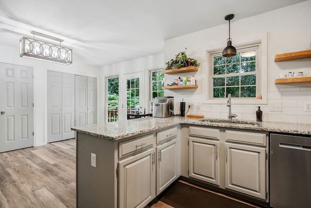 kitchen with decorative backsplash, hardwood / wood-style floors, gray cabinets, and light stone counters