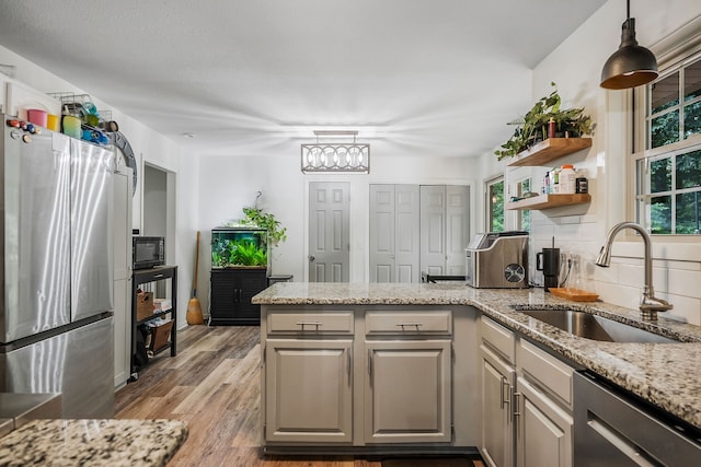 kitchen featuring appliances with stainless steel finishes, light wood-type flooring, a wealth of natural light, and sink