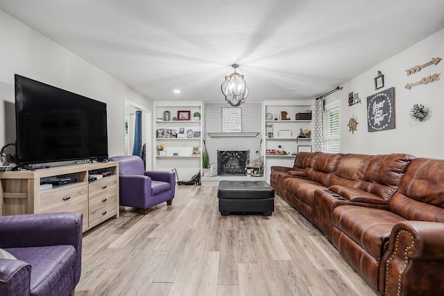 living room featuring light hardwood / wood-style floors, brick wall, a brick fireplace, and a chandelier