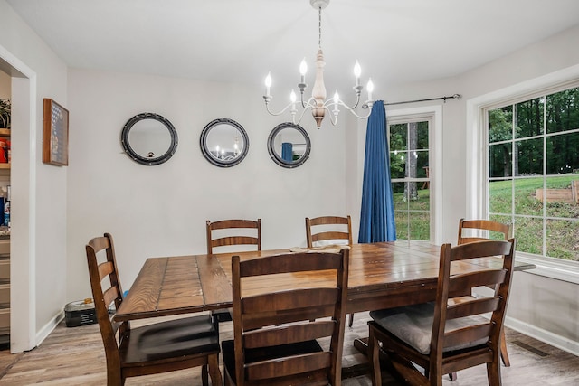 dining area with light hardwood / wood-style floors, a wealth of natural light, and a chandelier