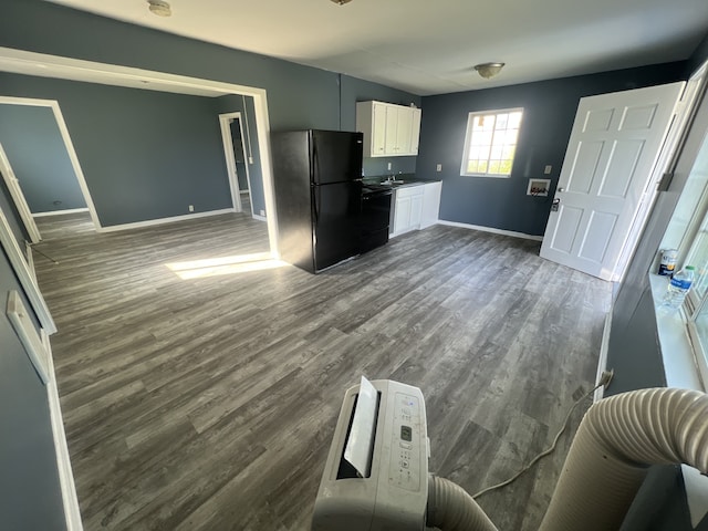 kitchen with sink, black refrigerator, hardwood / wood-style flooring, dishwasher, and white cabinetry