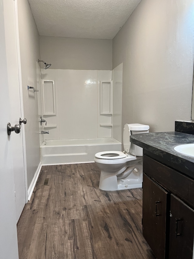 full bathroom with wood-type flooring, bathtub / shower combination, a textured ceiling, vanity, and toilet