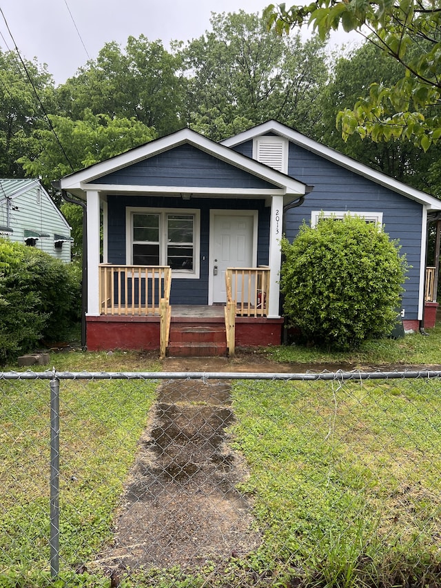 bungalow featuring covered porch and a front yard