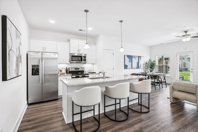 kitchen featuring backsplash, dark wood-type flooring, light stone counters, white cabinetry, and stainless steel appliances