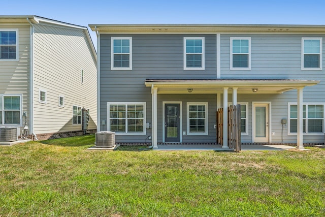 rear view of property with central air condition unit and a lawn