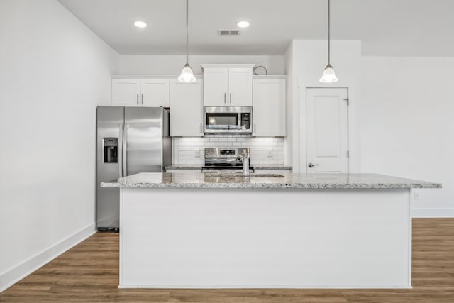 kitchen featuring white cabinetry, appliances with stainless steel finishes, hardwood / wood-style flooring, and an island with sink