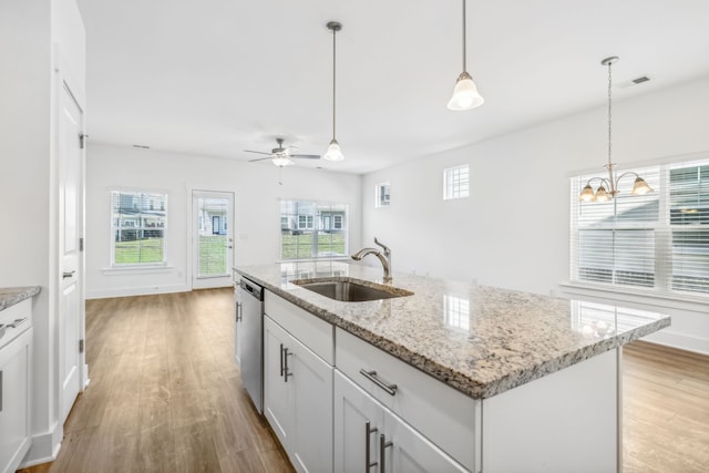 kitchen featuring sink, an island with sink, light hardwood / wood-style floors, dishwasher, and pendant lighting