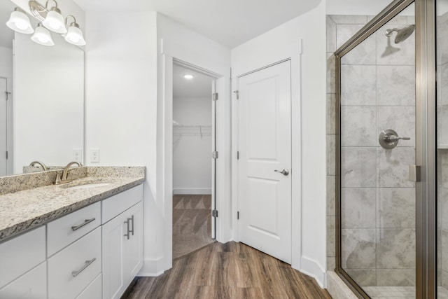 bathroom featuring hardwood / wood-style floors, walk in shower, and vanity