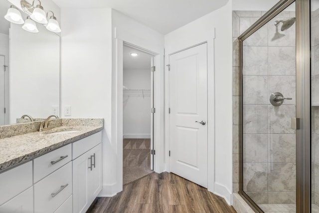 bathroom featuring hardwood / wood-style floors, a notable chandelier, vanity, and walk in shower