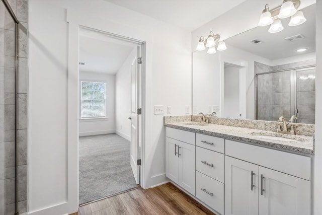 bathroom featuring hardwood / wood-style flooring, vanity, and a shower with shower door