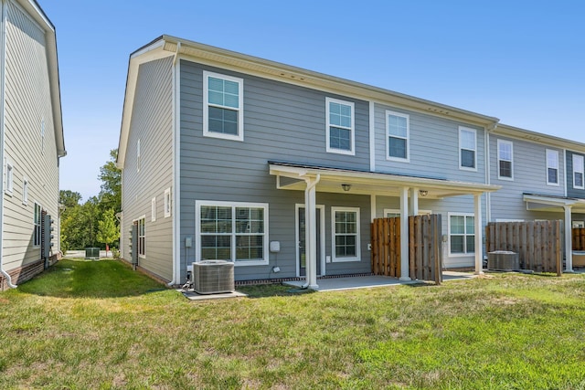 back of house featuring central AC unit and a lawn