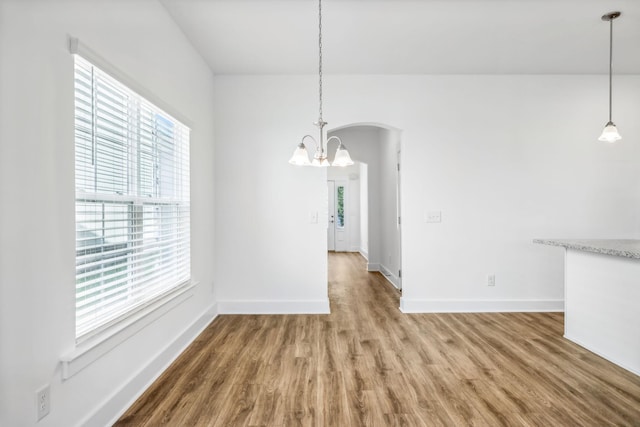 unfurnished dining area featuring wood-type flooring and a notable chandelier