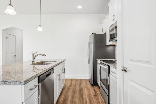 kitchen with sink, wood-type flooring, white cabinetry, stainless steel appliances, and pendant lighting