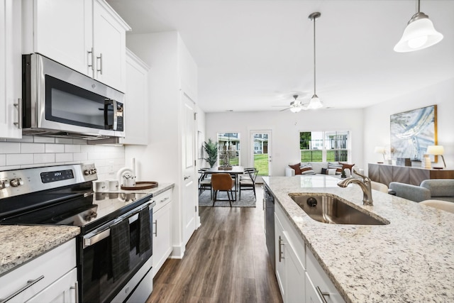 kitchen featuring tasteful backsplash, hanging light fixtures, stainless steel appliances, sink, and white cabinetry