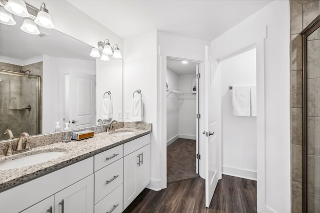 bathroom with wood-type flooring, dual bowl vanity, and an enclosed shower