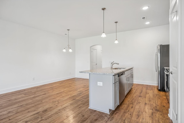 kitchen with a center island with sink, stainless steel appliances, sink, and decorative light fixtures