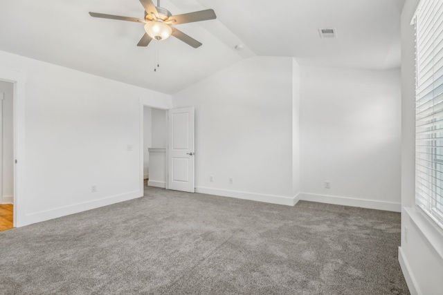 carpeted empty room featuring ceiling fan, vaulted ceiling, and a healthy amount of sunlight