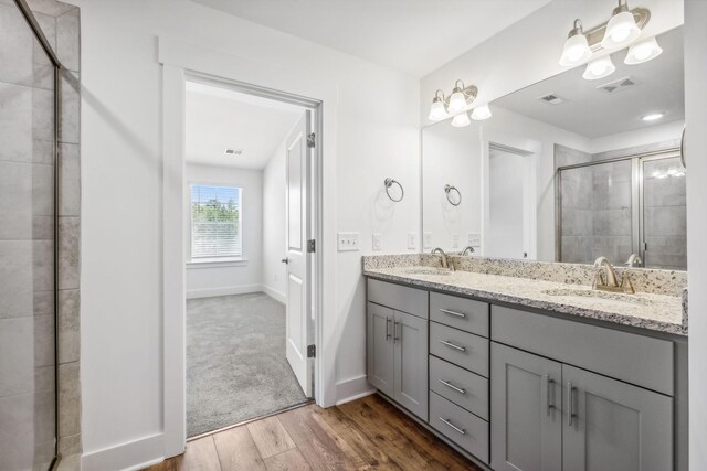 bathroom with a shower with door, double sink vanity, and wood-type flooring