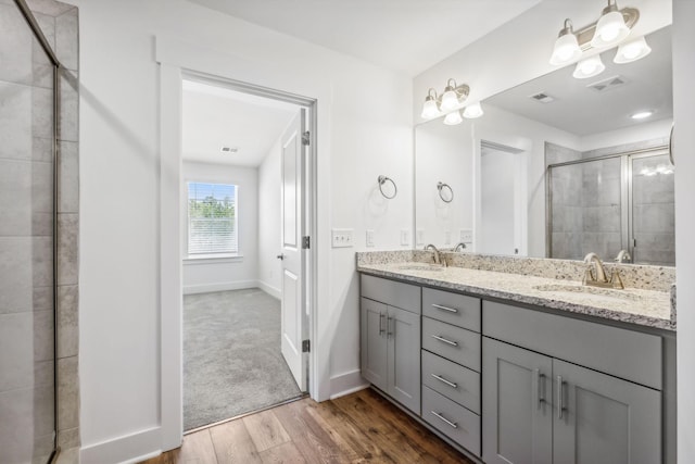 bathroom with hardwood / wood-style flooring, vanity, and a shower with door