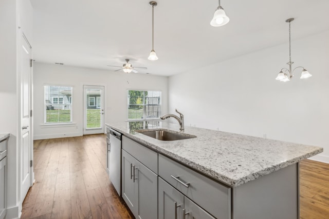 kitchen with sink, ceiling fan with notable chandelier, a kitchen island with sink, and light hardwood / wood-style floors