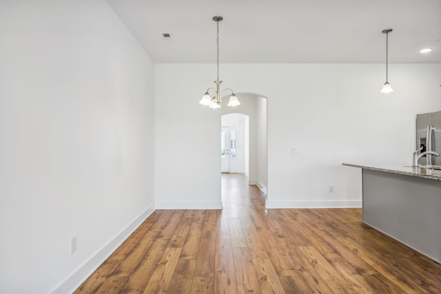 unfurnished living room featuring hardwood / wood-style flooring, sink, and a chandelier