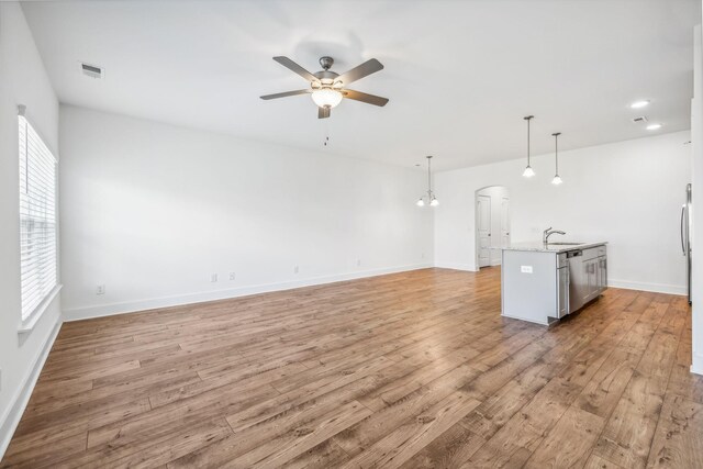 unfurnished living room featuring ceiling fan, light wood-type flooring, and sink