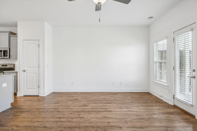 unfurnished dining area with ceiling fan and light wood-type flooring