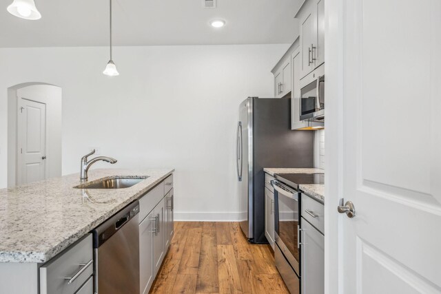 kitchen with sink, decorative light fixtures, appliances with stainless steel finishes, light hardwood / wood-style floors, and gray cabinets