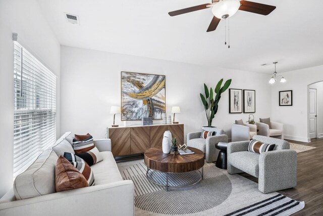 living room with ceiling fan with notable chandelier and wood-type flooring