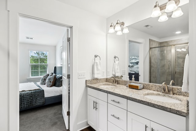 bathroom featuring dual vanity and a shower with shower door