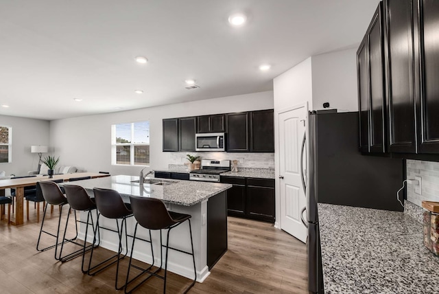 kitchen with sink, stainless steel appliances, a breakfast bar, and light hardwood / wood-style flooring