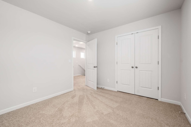 unfurnished bedroom with light carpet and a closet