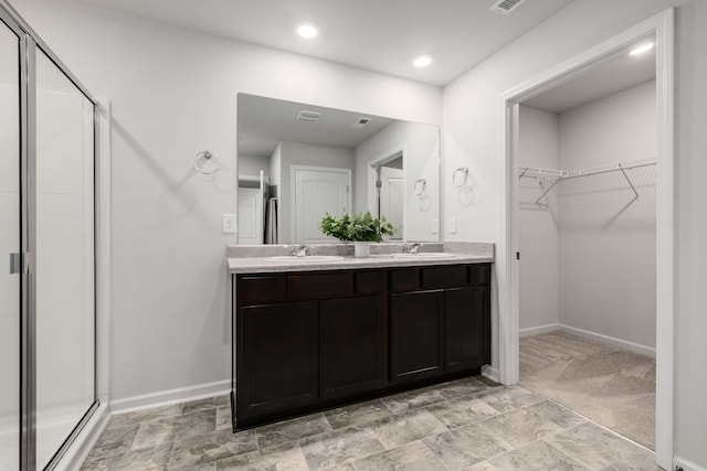 bathroom featuring dual vanity, a shower with door, and tile patterned floors