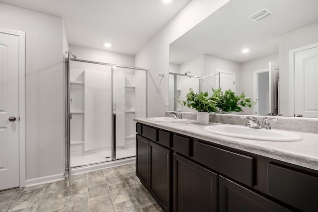 bathroom with tile patterned flooring, an enclosed shower, and double sink vanity