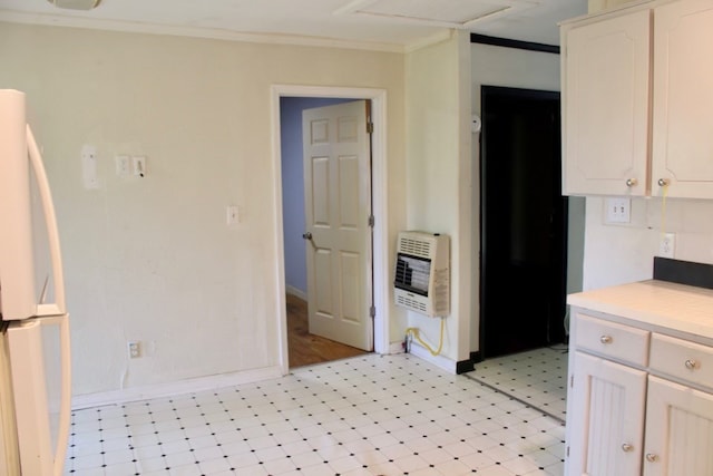 kitchen with crown molding, white cabinets, heating unit, and white refrigerator