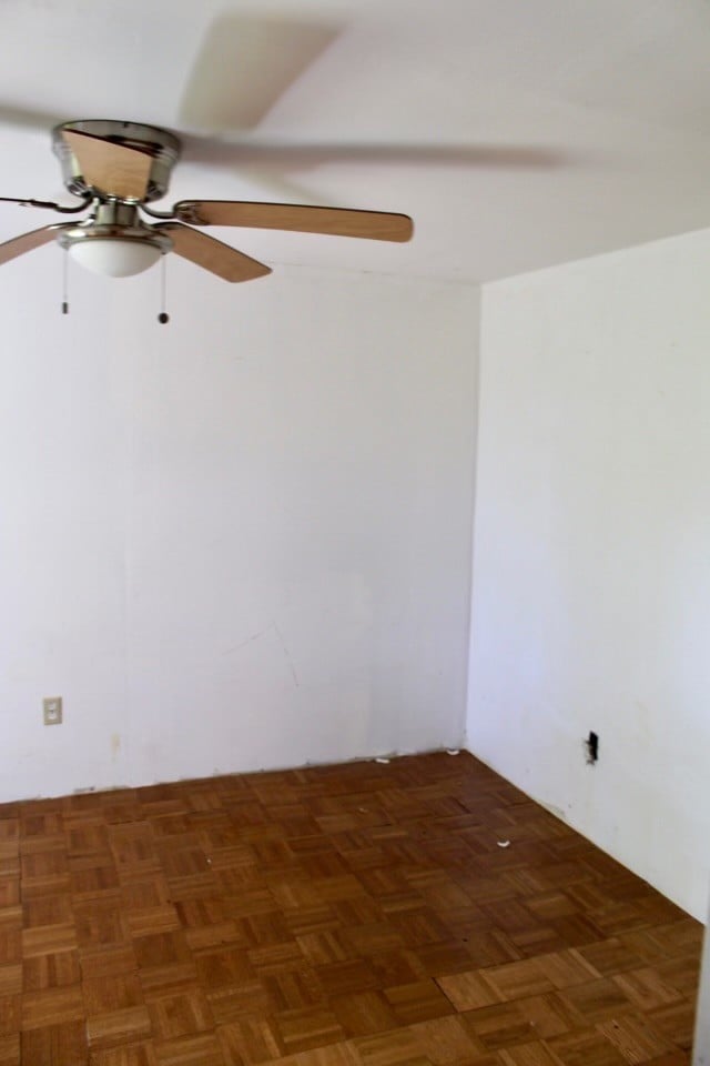 spare room with ceiling fan and dark parquet flooring